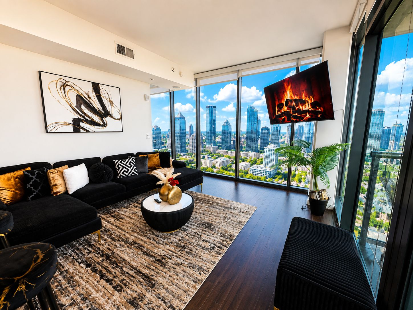 A modern living room with a black sofa, a round coffee table, and a large TV screen displaying a fire.