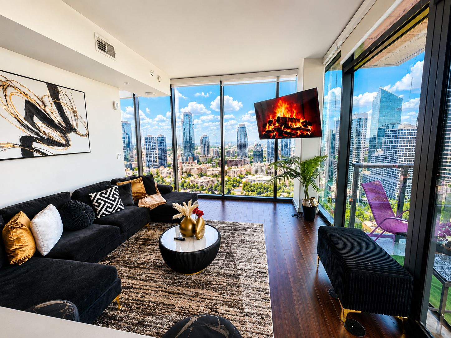 A modern living room with a city view, a black sofa, a coffee table, and a TV mounted on the wall.