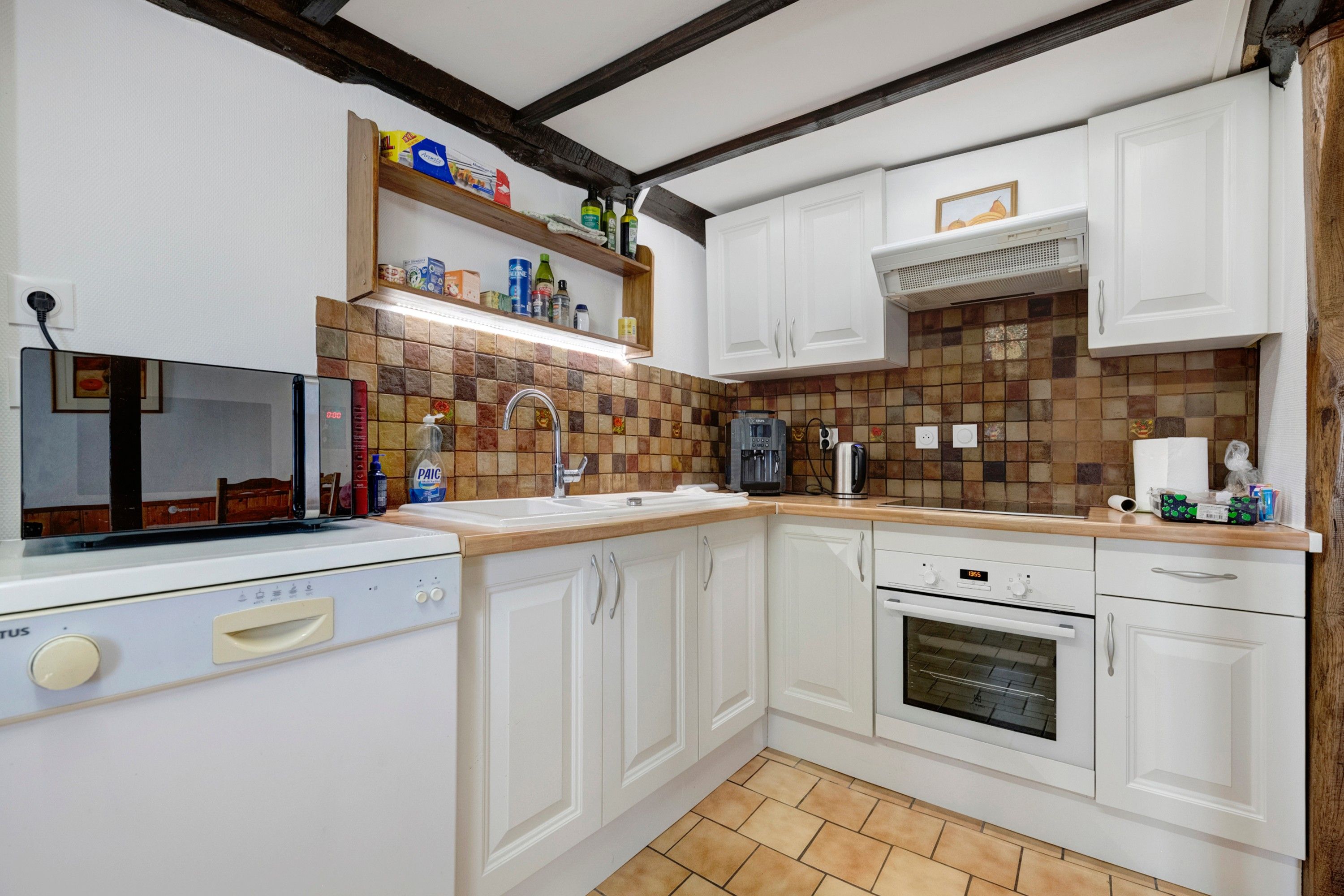 A kitchen with white cabinets, a tiled backsplash, a built-in oven, and a dishwasher.