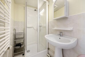 A bathroom with a glass shower enclosure, a white sink, and a towel rack.