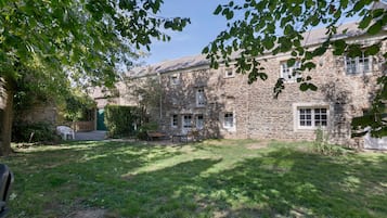 A stone building with a grassy yard and a wooden bench.