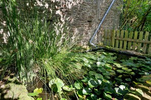 A garden with a stone wall, a wooden fence, and water lilies. - “La Cour Blanche L'Equestre” Room with Shared Terrace, Garden, and Wi-Fi (Castillon)