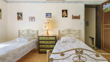 A bedroom with two single beds, a nightstand with a lamp, and a dresser with horse-themed drawers.
