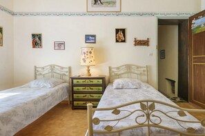A bedroom with two single beds, a nightstand with a lamp, and a dresser with horse-themed drawers. - “La Cour Blanche L'Equestre” Room with Shared Terrace, Garden, and Wi-Fi (Castillon)