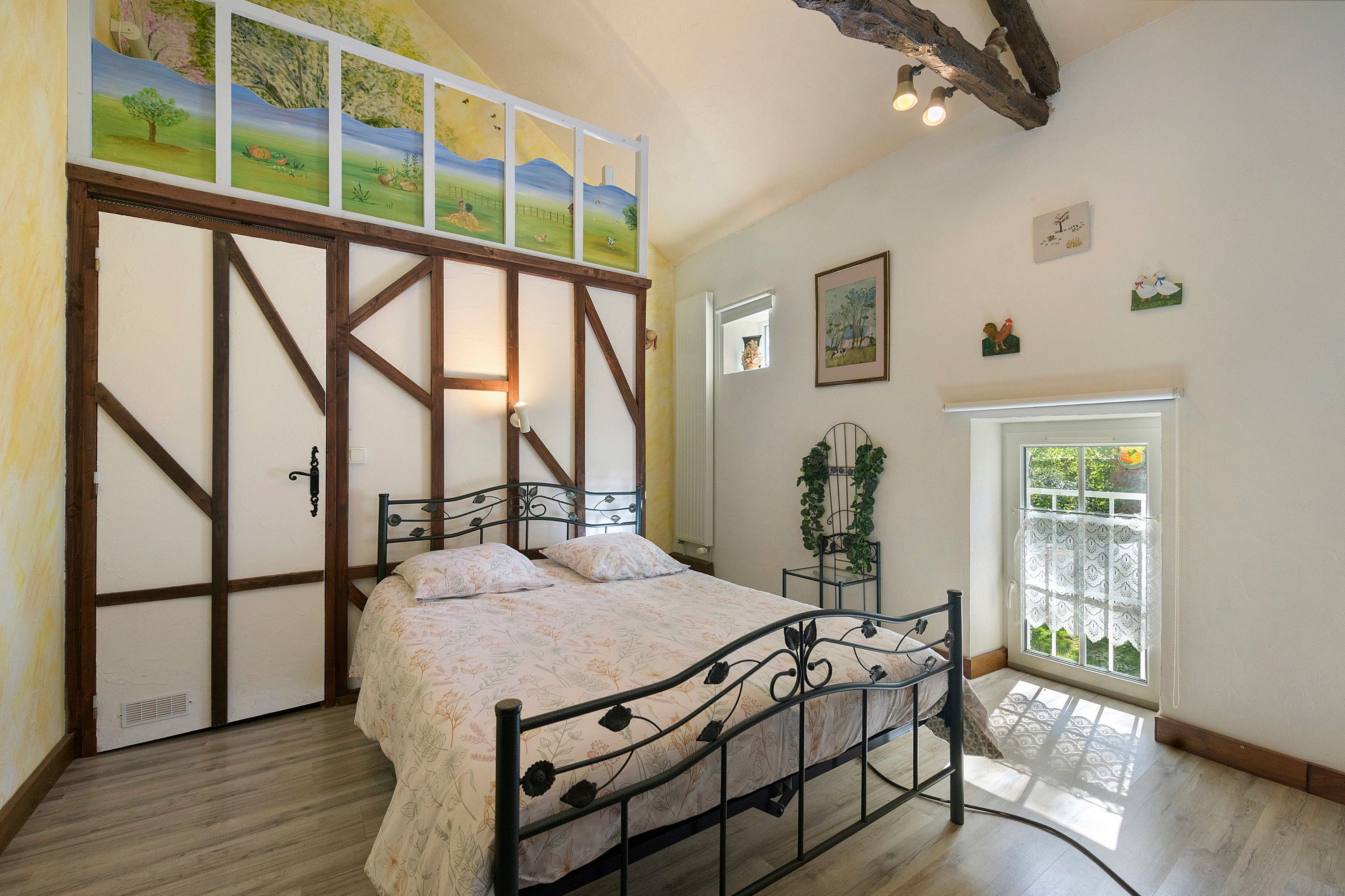 Une chambre à coucher avec un lit, une fenêtre donnant sur un beau paysage et une porte ornée d ’un tableau.