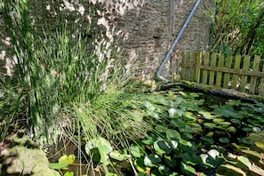 A garden with a stone wall, a wooden fence, and water lilies. - Bed and Breakfast 'Chambre - La Campagne' with Shared Terrace, Shared Garden and Wi-Fi (Castillon)