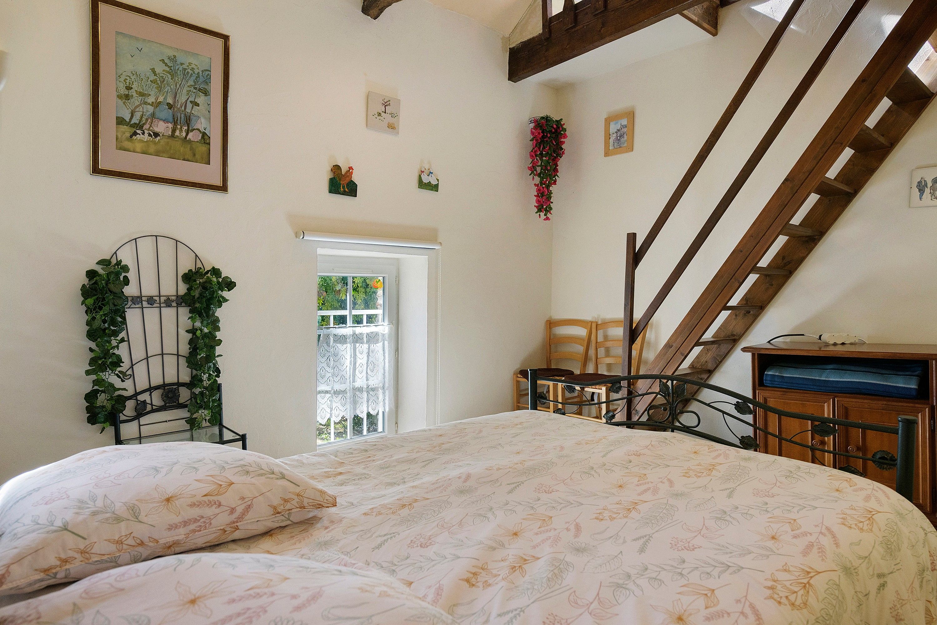 A bedroom with a bed, a window, a staircase, and a door.