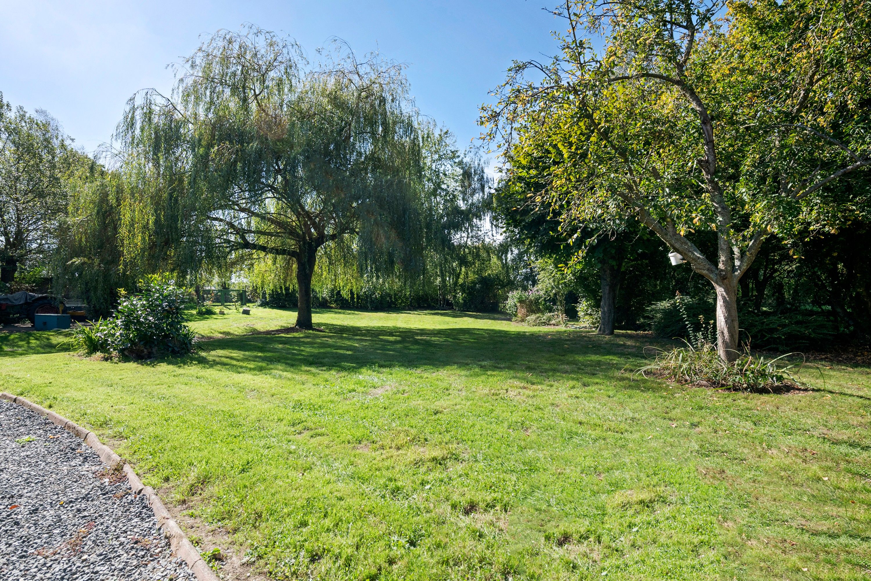 A well-maintained grassy area with trees and a gravel path.