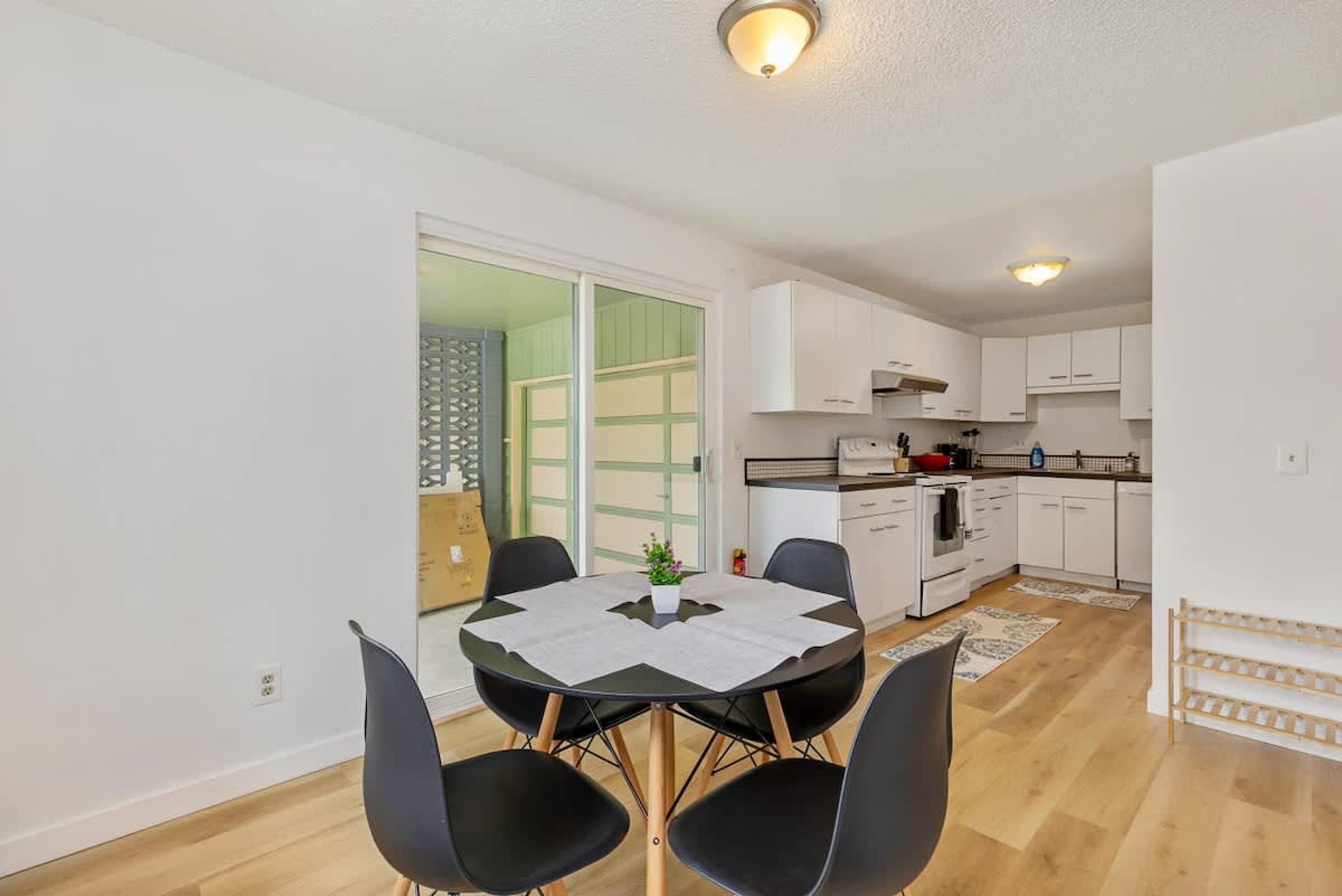 Una cocina compacta con armarios blancos, estufa y comedor con mesa y sillas.