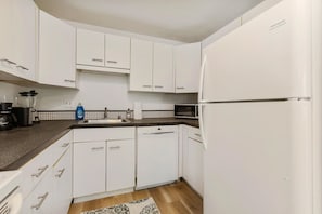 A kitchen with white cabinets, a microwave, a dishwasher, and a refrigerator. - Relaxing Lynnwood Getaway   Two Beds with Parking (Lynnwood)