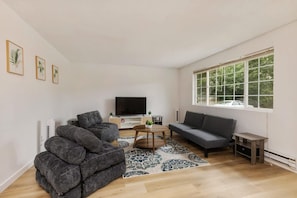 A modern living room with a sofa, two armchairs, a coffee table, and a flat-screen TV. - Relaxing Lynnwood Getaway   Two Beds with Parking (Lynnwood)