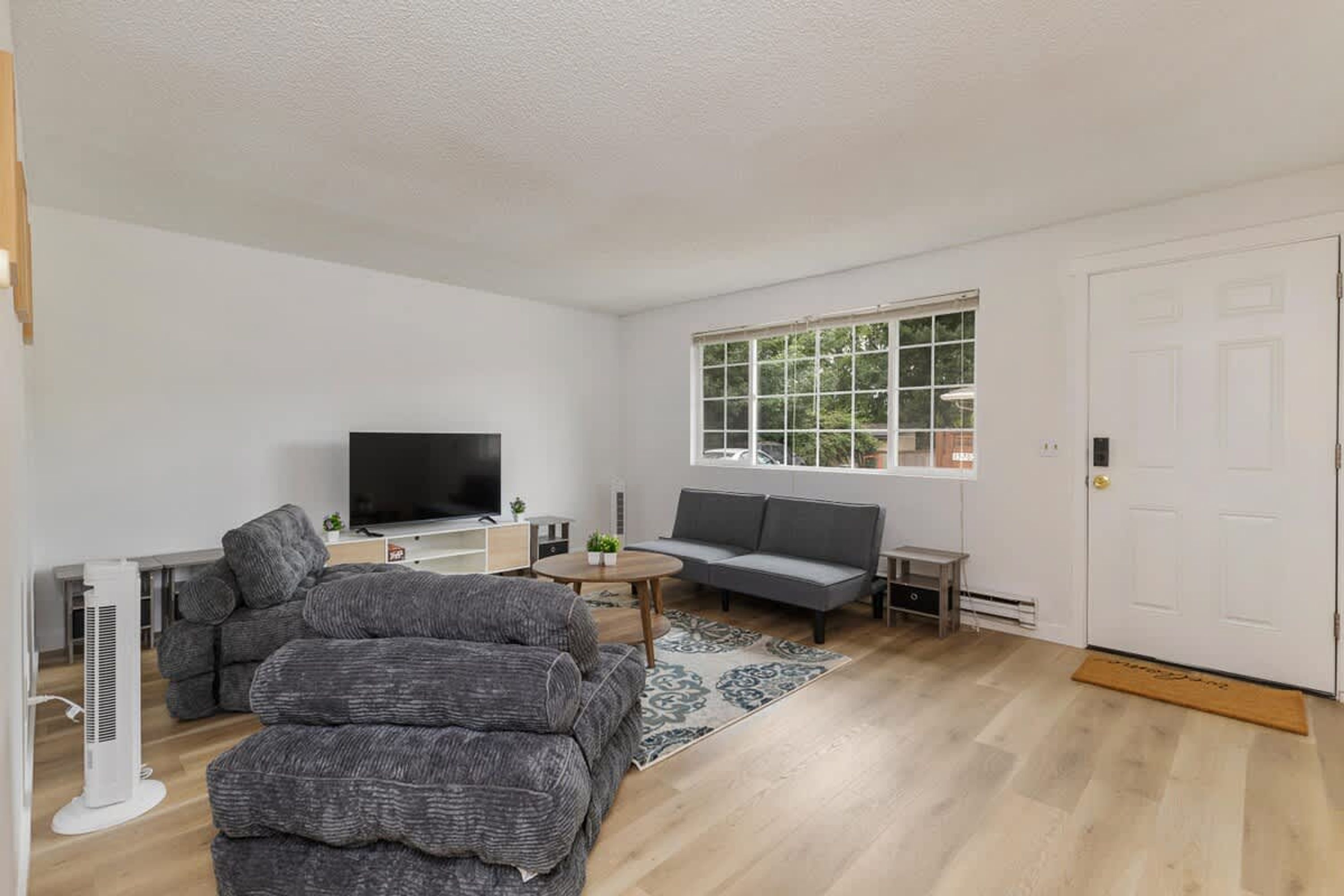 Een moderne woonkamer met een bank, een televisie en een groot raam.