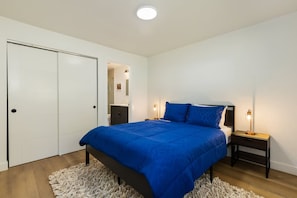 A bedroom with a bed, nightstands, a wardrobe, and a light fixture. - Stylish Eastside 3BR Family Home   Prime Location (Bellevue)