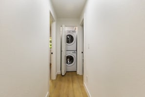 A narrow hallway with a double-door laundry room at the end. - Stylish Eastside 3BR Family Home   Prime Location (Bellevue)