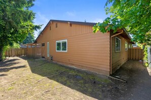 A single-story wooden house with a fenced yard, a small window, and a door. - Stylish Eastside 3BR Family Home   Prime Location (Bellevue)