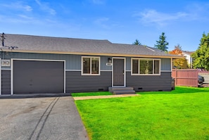 A single-story house with a garage, a front porch, and a well-maintained lawn. - Family-Friendly 2BR Home in Lynnwood w  Parking (Lynnwood)