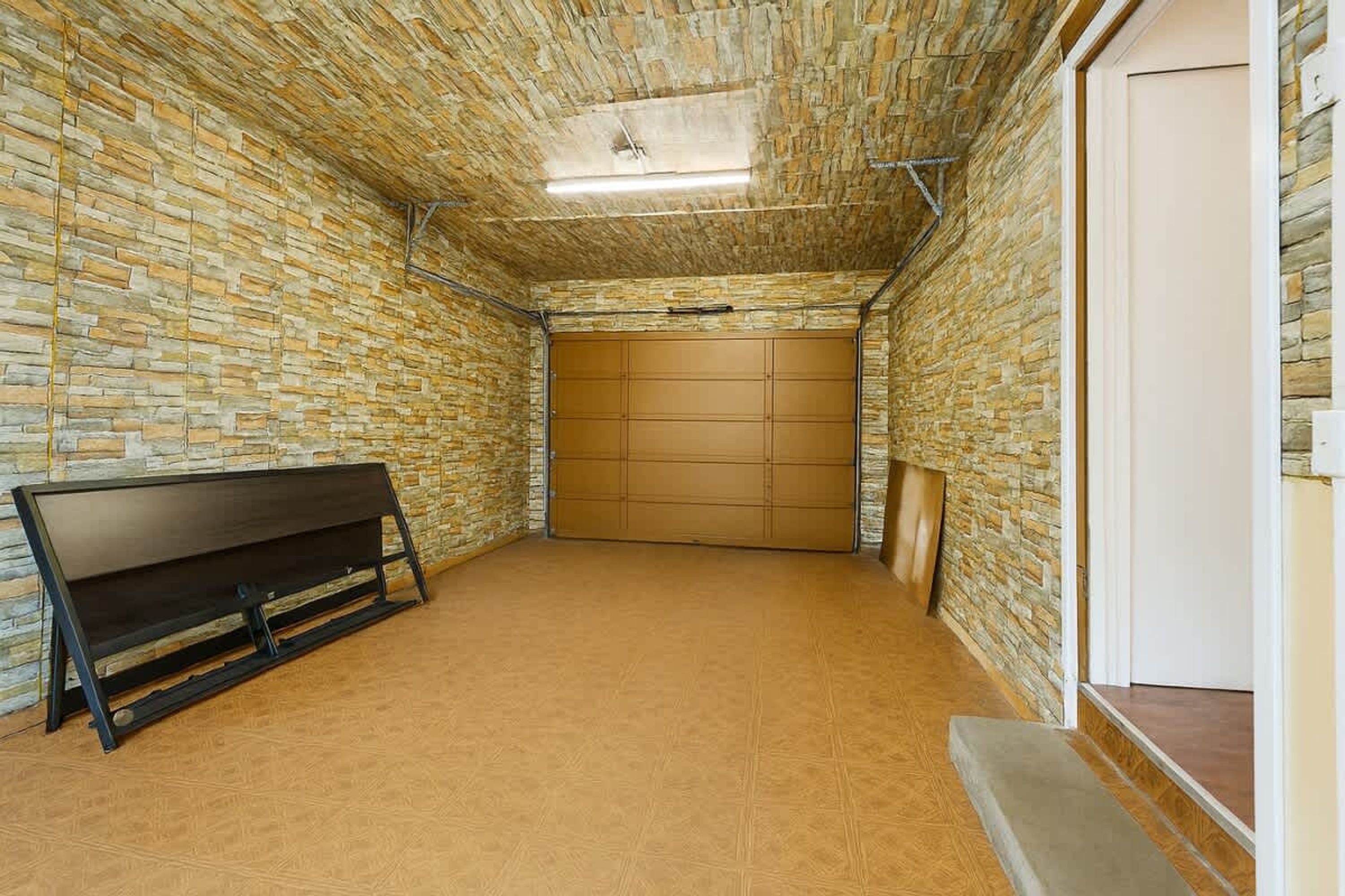 Ein Zimmer mit Steinwänden, einer Bank und einer Tür.