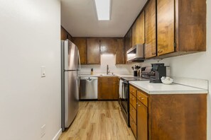 A kitchen with wooden cabinets, stainless steel appliances, and a white countertop. - Comfortable Townhouse in Ash Way Lynnwood (Lynnwood)