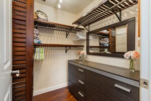 Ein begehbarer Kleiderschrank mit Holzböden, einem Schminktisch mit Spiegel und einer Kommode.