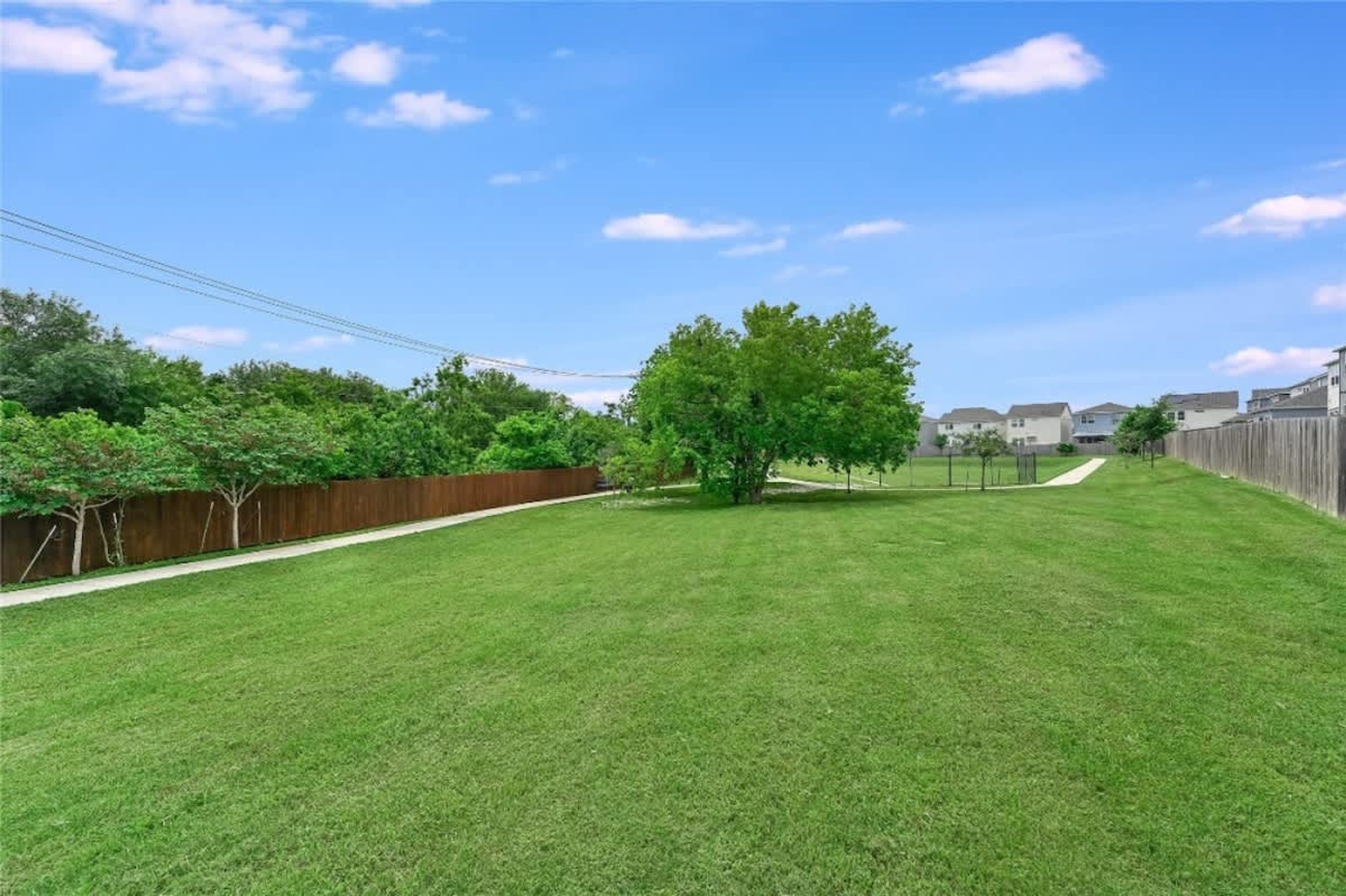 Ein Garten mit Holzzaun, einem Baum und blauem Himmel.