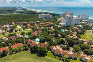 Zona residencial costera con varios edificios, incluyendo hoteles y casas, rodeada de vegetación y una playa.