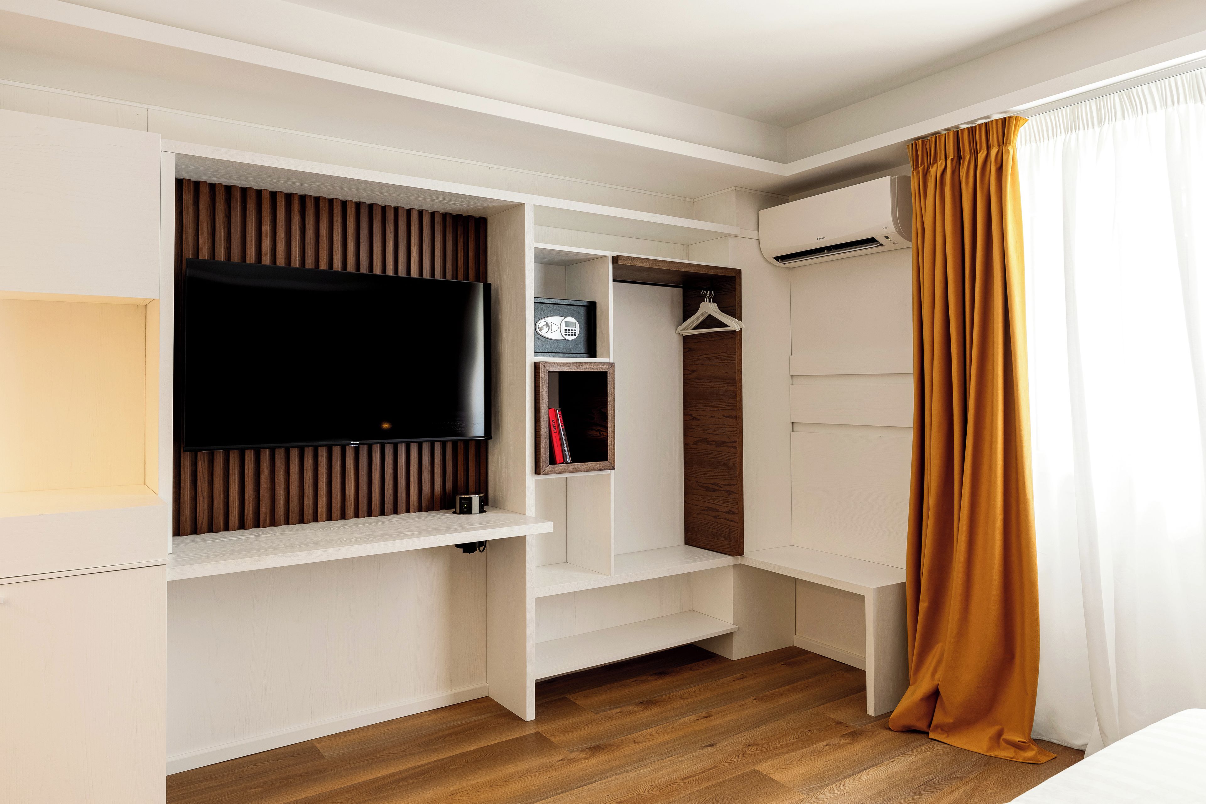 Habitación de hotel con televisión integrada, armario y perchero.