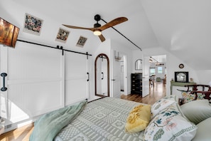Un dormitorio con una cama grande, un ventilador de techo y vistas al comedor.