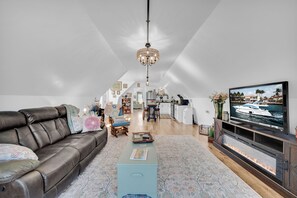 A spacious living room with a leather sofa, a coffee table, a television, and a fireplace.