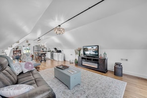 Un loft espacioso con techos altos, una cocina moderna, una sala de estar con sofá y mesa de centro, y un televisor.
