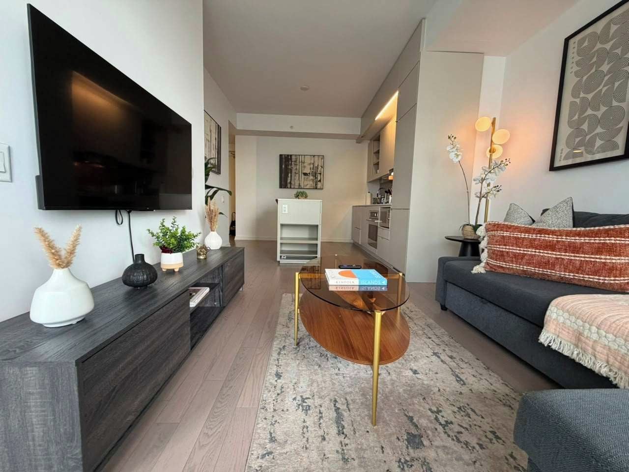 Un salon moderne avec un téléviseur à écran plat, une table basse en verre, un canapé et un tapis.