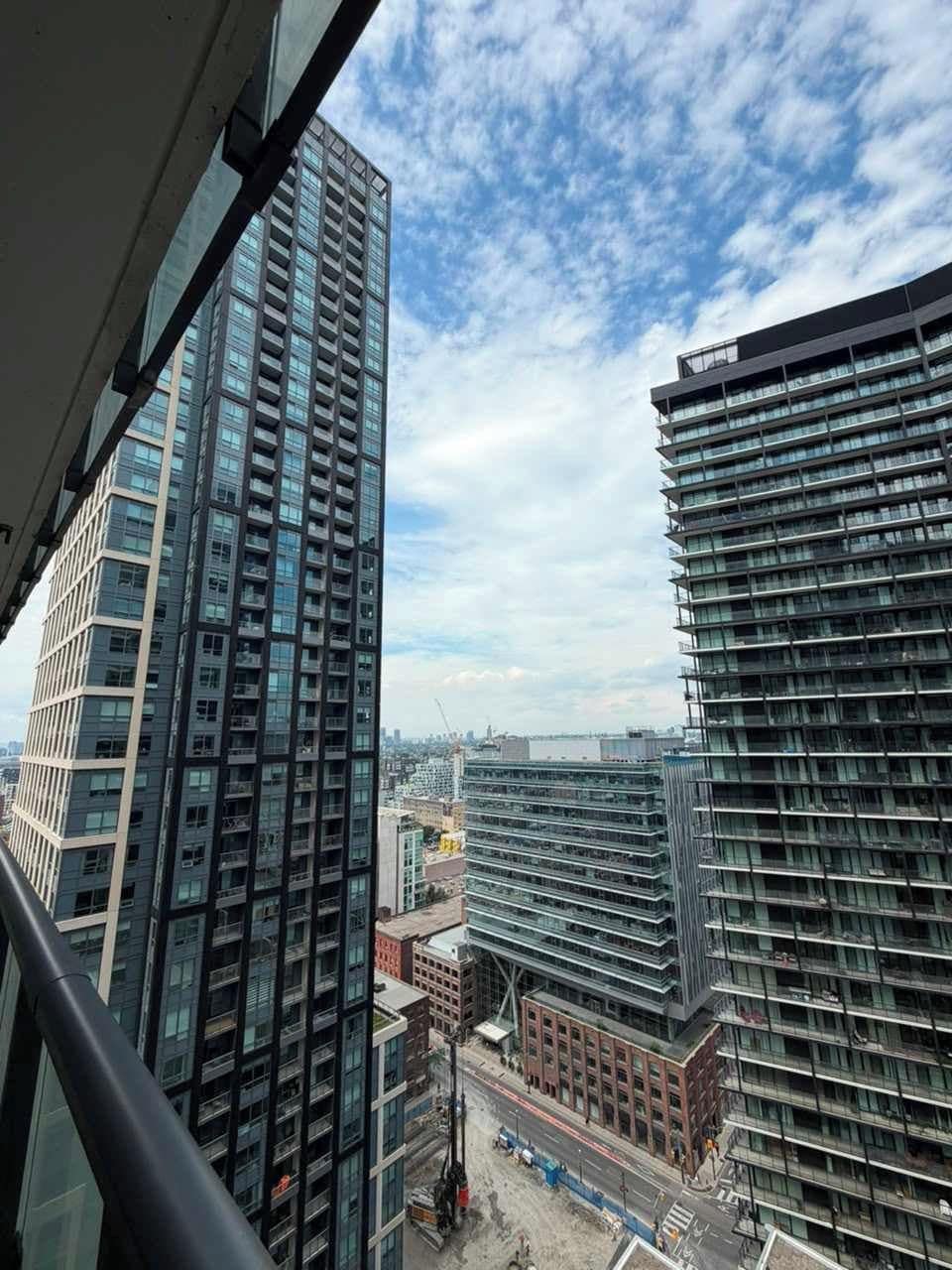 Un edificio alto con varios pisos y balcones, visto desde una ventana con vista a una obra en construcción.