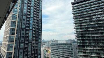 Un edificio alto con varios pisos y balcones, visto desde una ventana con vista a una obra en construcción.
