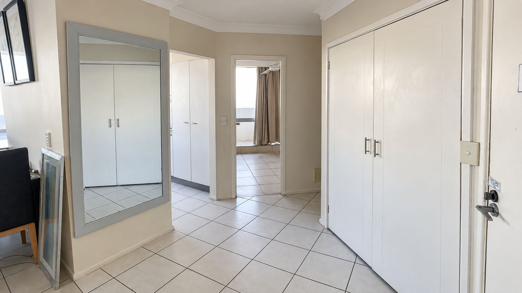 A hotel room with a large mirror, a wardrobe, and a door leading to a balcony.