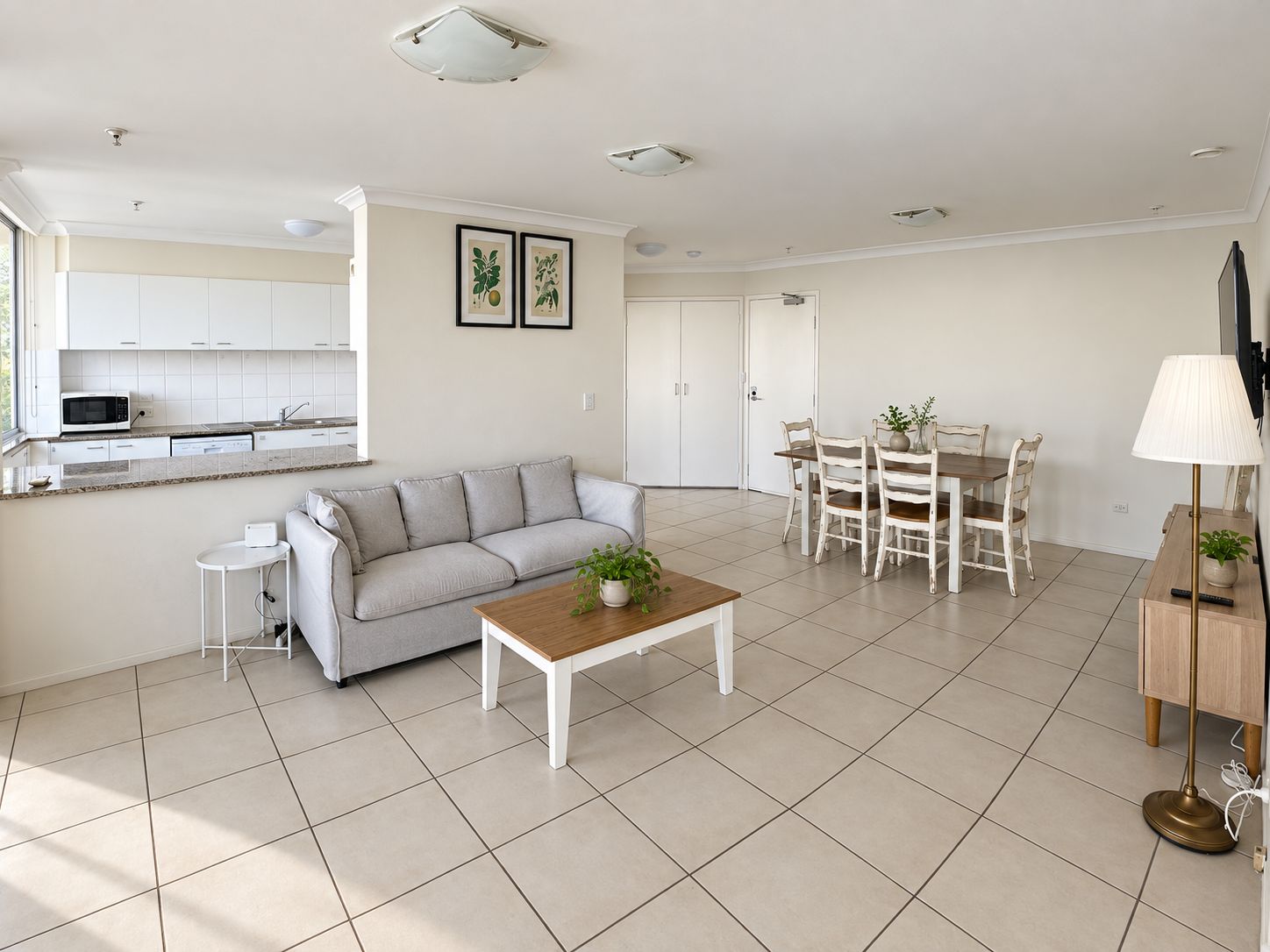 A modern living room with a sofa, coffee table, and dining area with chairs.