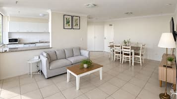 A modern living room with a sofa, coffee table, and dining area with chairs.