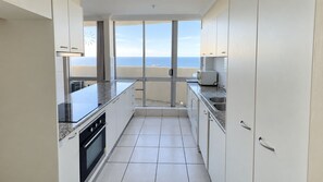Eine moderne Küche mit Meerblick, ausgestattet mit weißen Schränken, einer Granitabdeckung und einem Einbauofen.