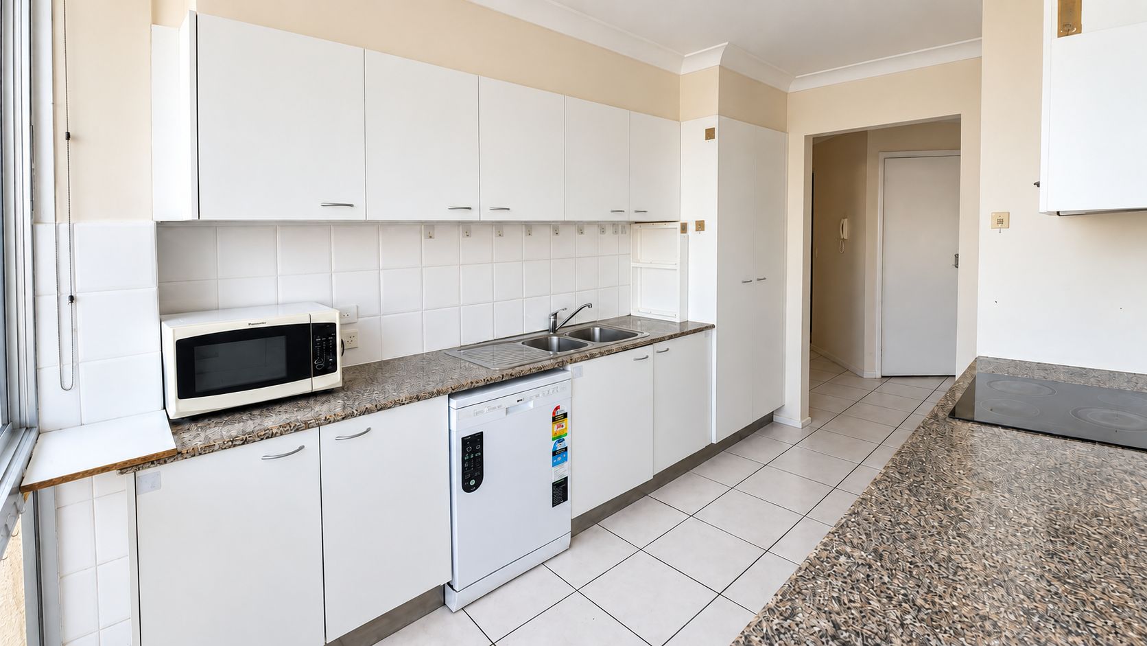 A kitchen with white cabinets, a microwave, a dishwasher, and a granite countertop.
