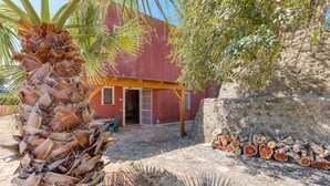 A rustic building with a wooden pergola, a palm tree, and a stone wall with stacked logs. - Apartment 'Le Colonie - Pineta' with Private Terrace and Shared Garden (Presicce)