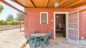 A covered outdoor patio with a table and chairs, a wooden ceiling, and a view of a garden. - Apartment 'Le Colonie - Pineta' with Private Terrace and Shared Garden (Presicce)