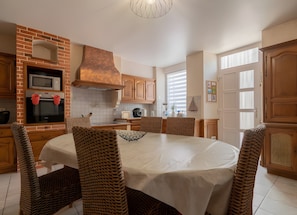 Una cucina con parete rivestita in mattoni, mobili in legno, un tavolo rotondo con sedie e un forno a incasso.