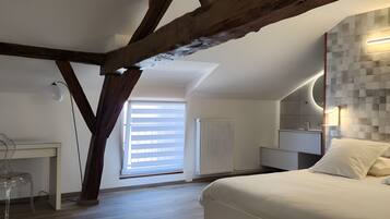 Ein modernes Schlafzimmer mit freiliegenden Holzbalken, einem großen Bett, einem Schreibtisch und Blick ins Freie.