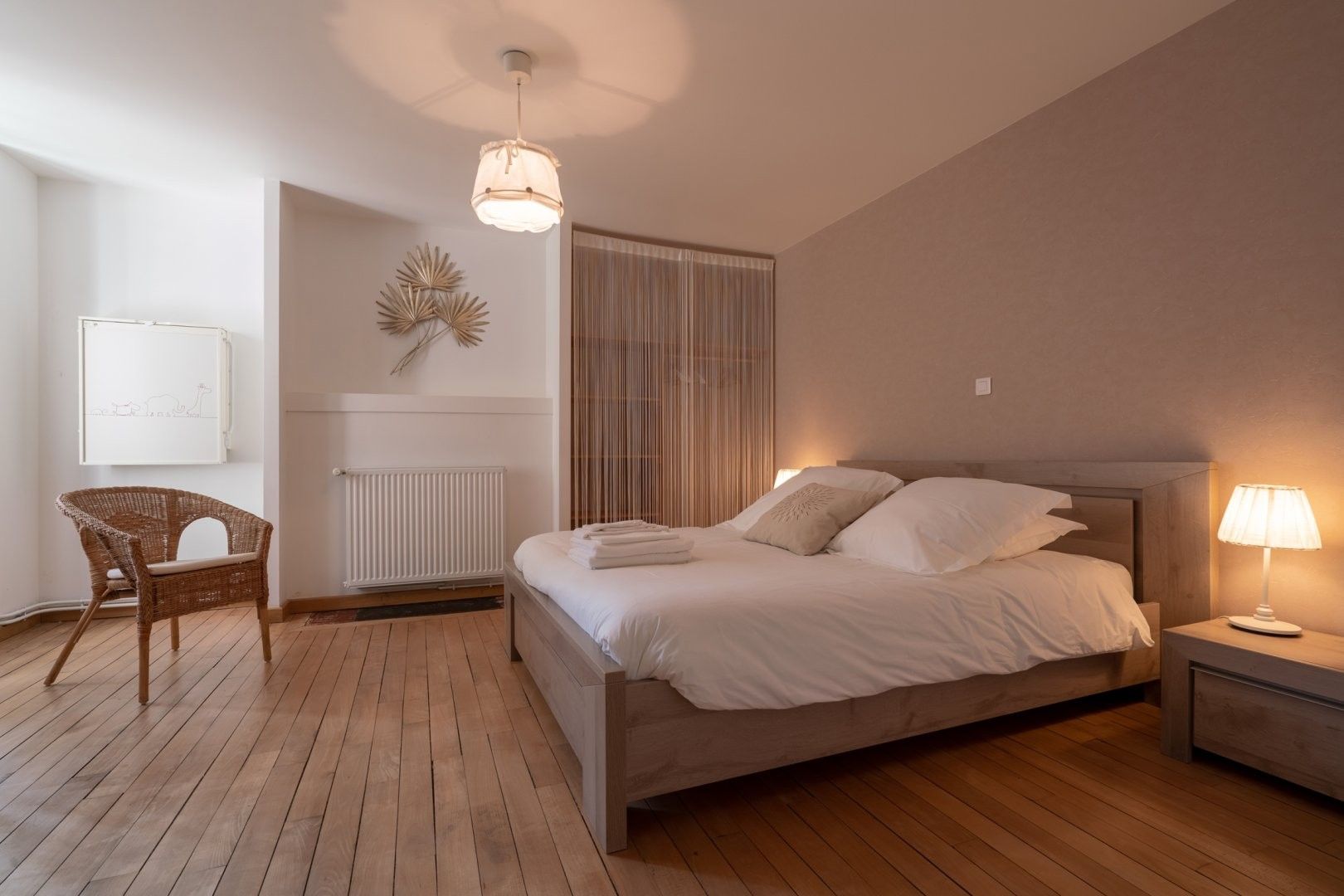 Ein Schlafzimmer mit einem Bett, einem Sessel, einem Nachttisch mit Lampe, einer Heizung und einer Wandleuchte.