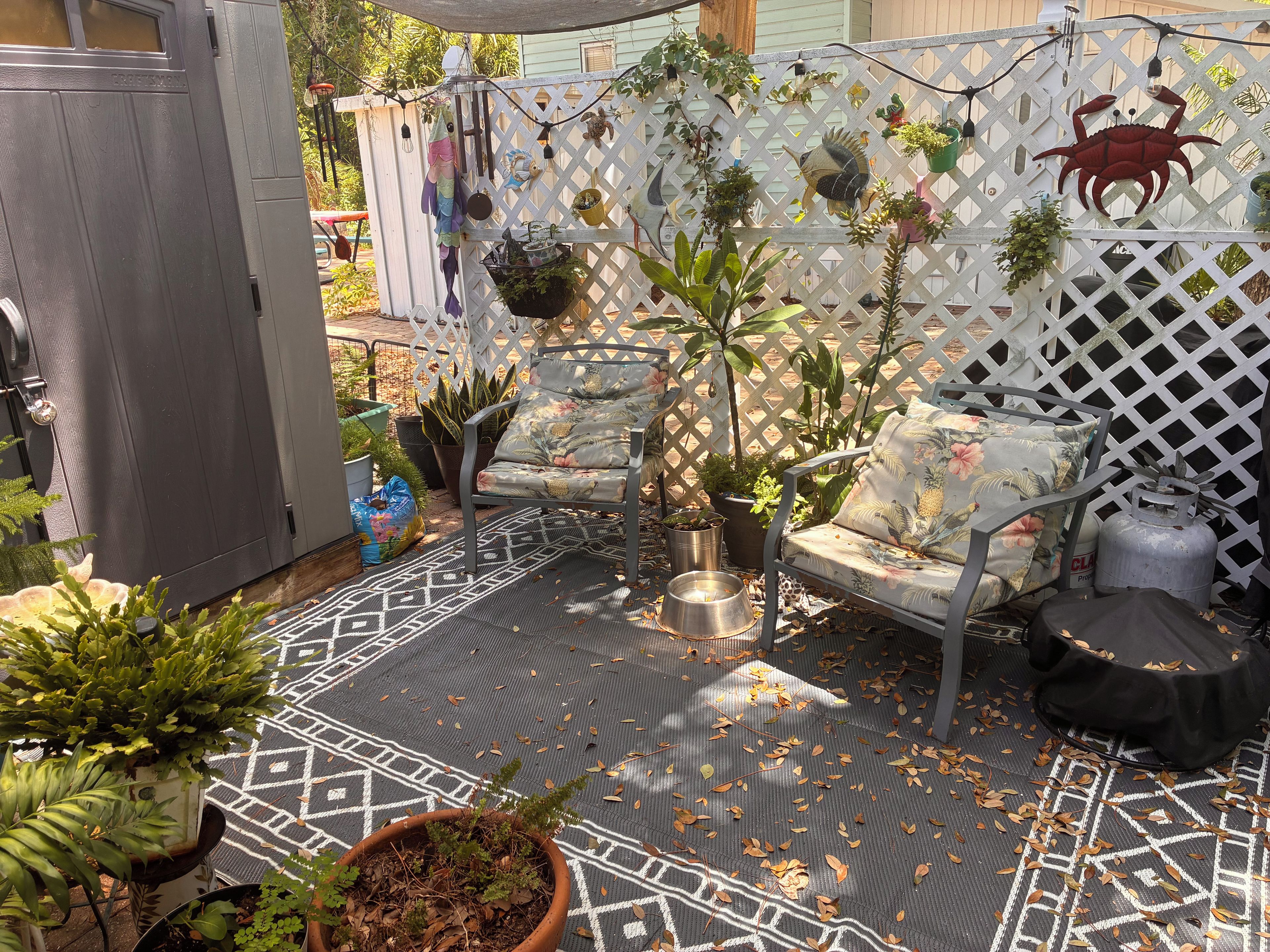 Un patio amueblado con plantas en macetas y un cerco decorativo.