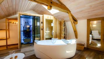 A modern bathroom with a large bathtub, wooden beams, and a glass door leading to a shower area.