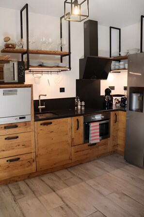 Una cuina moderna amb armaris de fusta, forn integrat i nevera d'acer inoxidable.