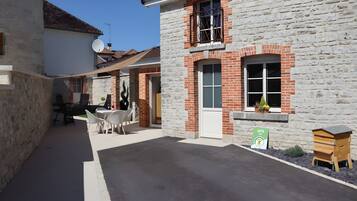 Une ruelle bordée de bâtiments en pierre, une table avec des chaises et une ruche.