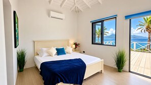 A bedroom with a bed, a nightstand, a window with a view, and an air conditioning unit.