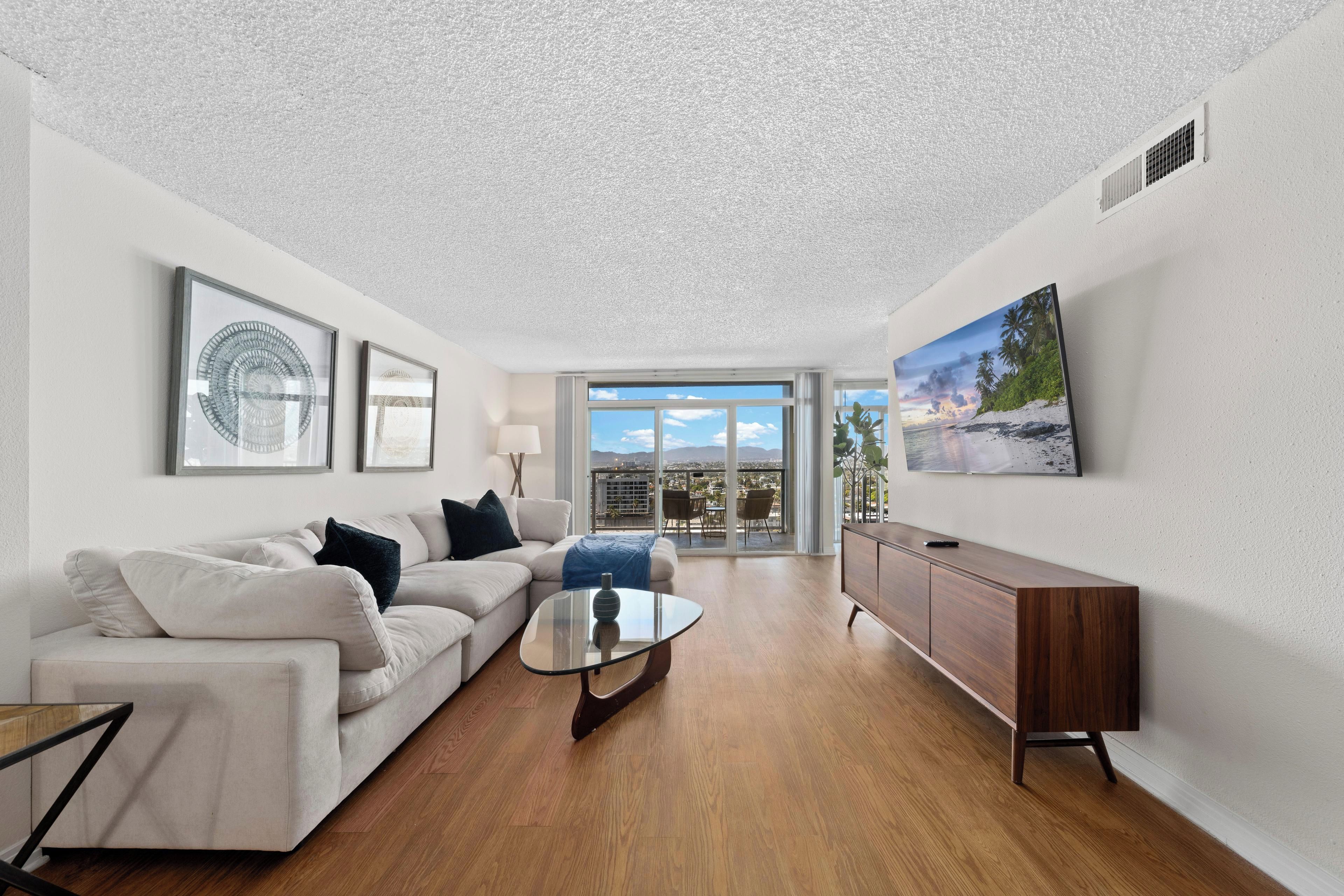 A modern living room with a sofa, coffee table, and a flat-screen TV mounted on the wall.