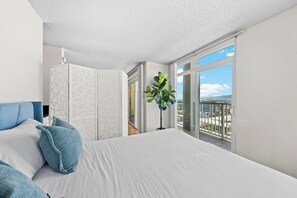 Ein modernes Schlafzimmer mit einem großen Bett, einem Kleiderschrank und einem Balkon mit Blick.