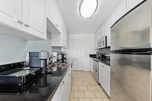 A modern kitchen with white cabinetry, a stainless steel refrigerator, a coffee maker, and a microwave. - Azure Horizon - 3 BR Ocean Views & Resort Pool (Marina del Rey)